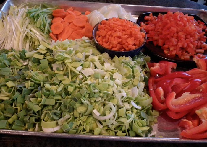 Close-up of a tray brimming with chopped vegetables (carrots, tomato, red peppers, and more).
