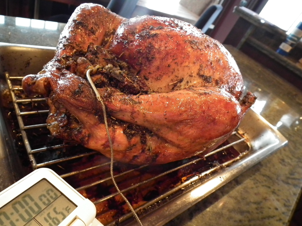 A roasted turkey cools in its roasting pan on a countertop, following the tips in Chef Nancy’s Christmas dinner serving guide.