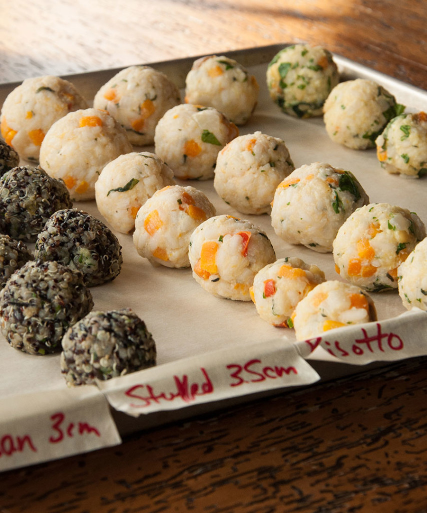 Close-up of a tray of rice balls (arancini) made from risotto and black quinoa.