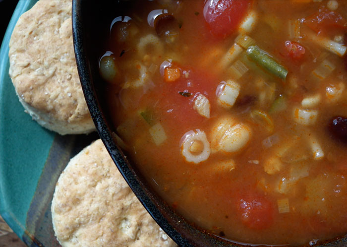 A beautiful bowl of hearty vegetable soup served with grain cakes.