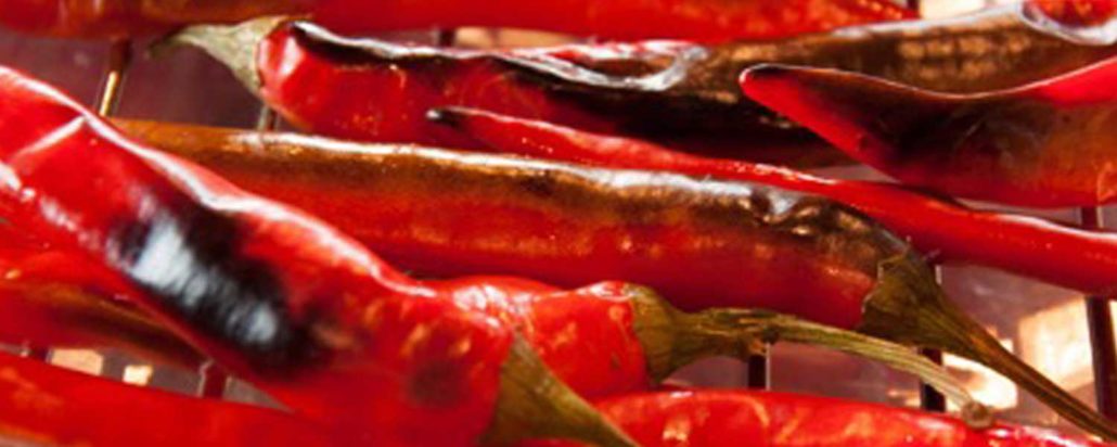 A close-up of roasted red chilli peppers ready to be used in this salsa recipe.