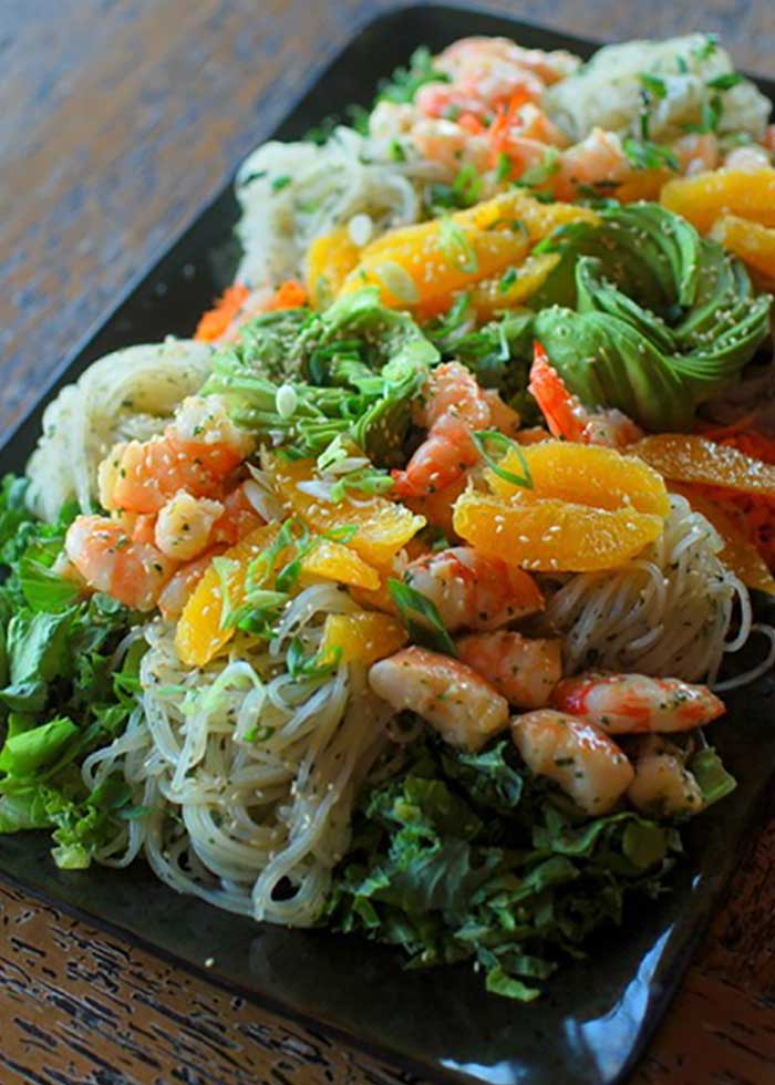 A hearty salad made with greens and noodles and topped with shrimp and tangerines.