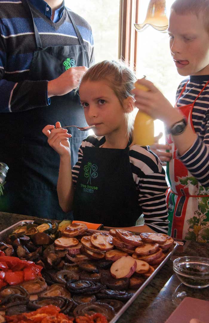 A young Tree House Kitchen student and her family taste-tasting her tzatziki creation with roasted vegetables.
