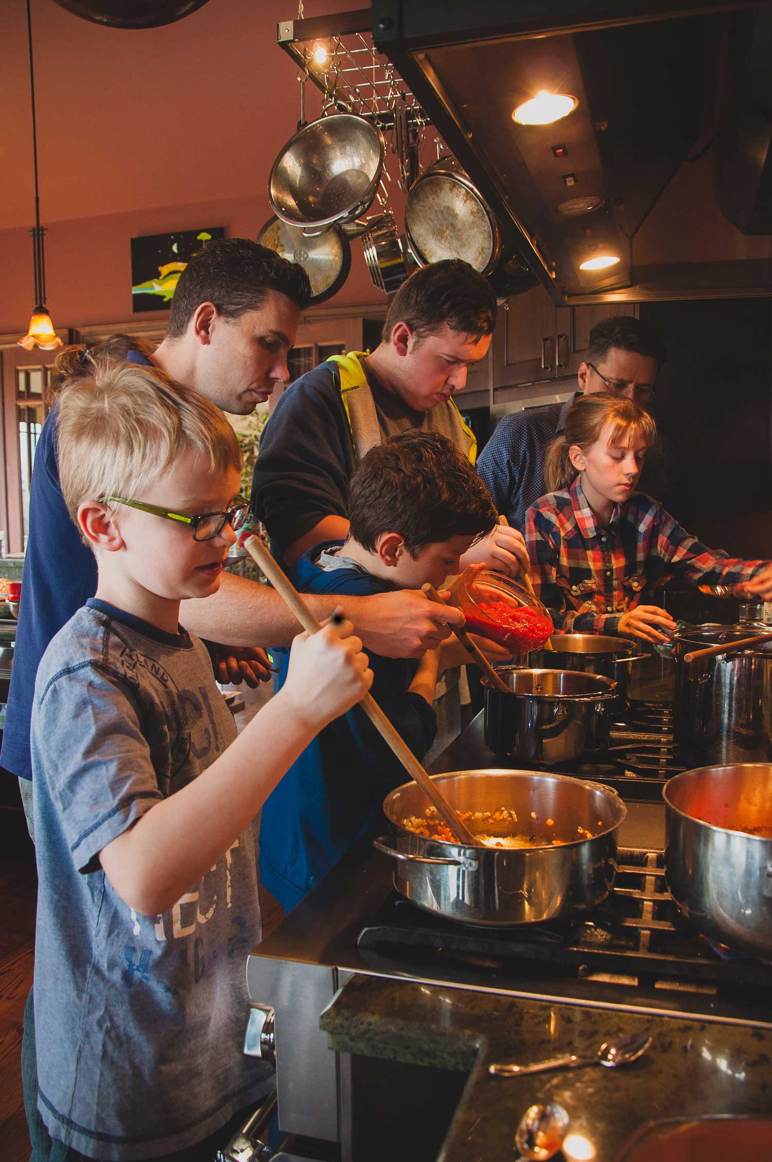 Young students making soup with their families at a past Tree House Kitchen family cooking class.  