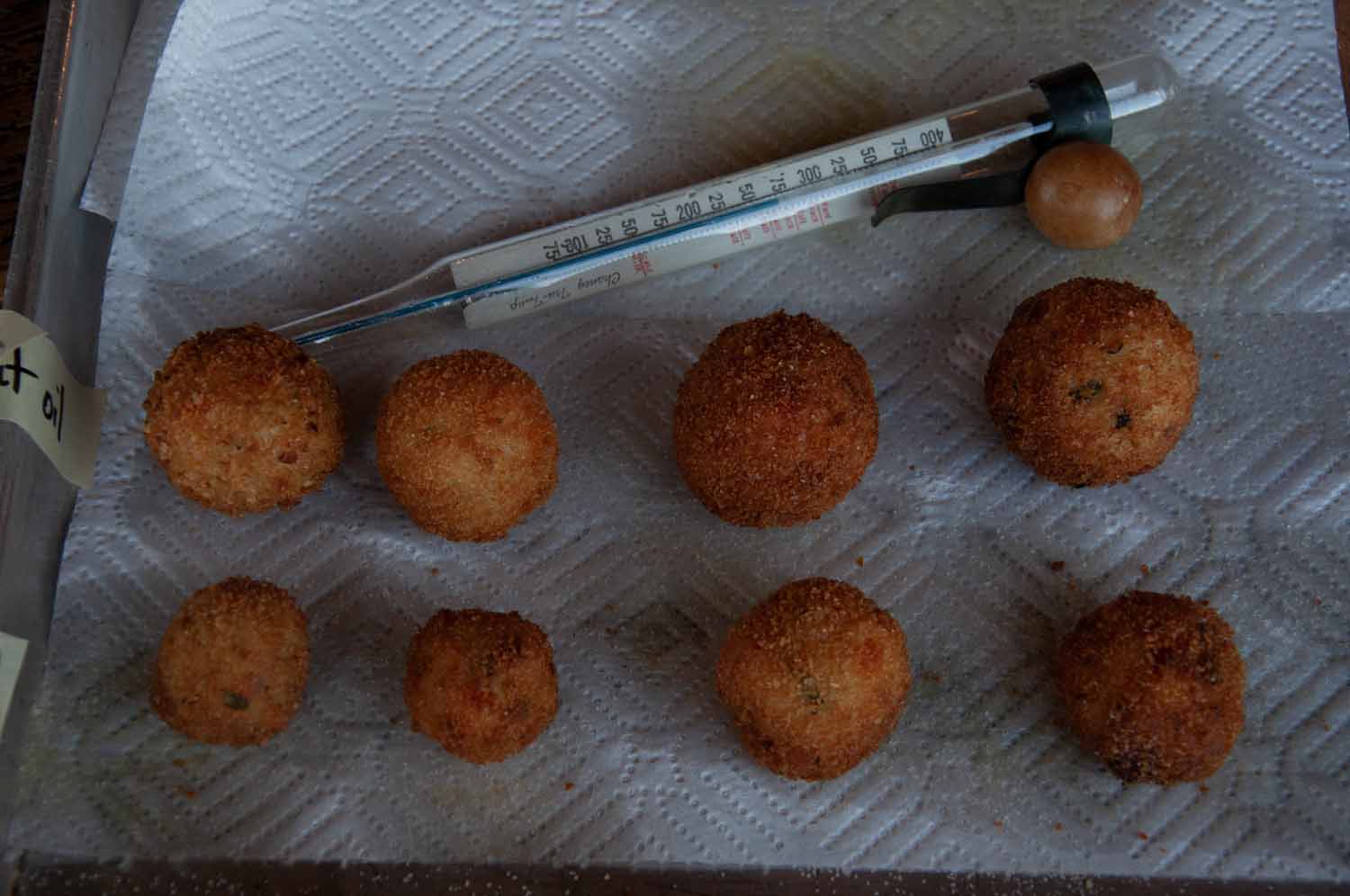 A tray of arancini (fried rice balls) and a thermometer to check the oil temperature. 